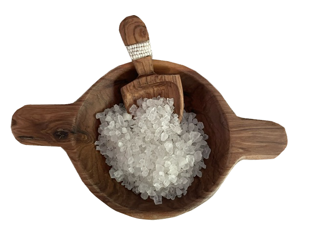 Dark wood salt bowl with beaded handle spoon, filled with salt crystals.